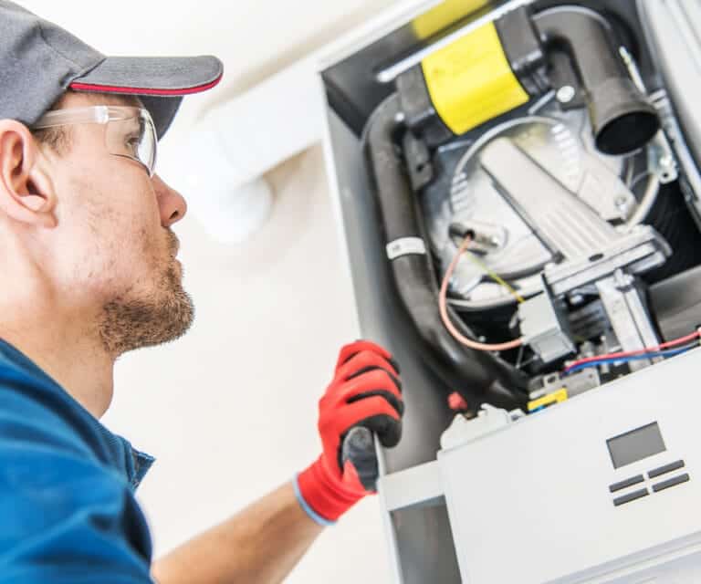 Technician repairing a furnace to ensure efficient heating performance, provided by Dynamic Heating & Cooling in Hamilton, ON.