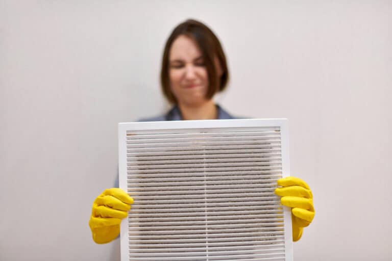 woman holding dirty and dusty ventilation grille, disgusted, vent cleaning service near me