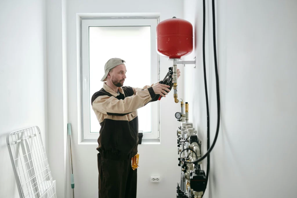 Man repairing red water tank in boiler room