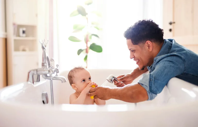 Father washing baby in bath tub