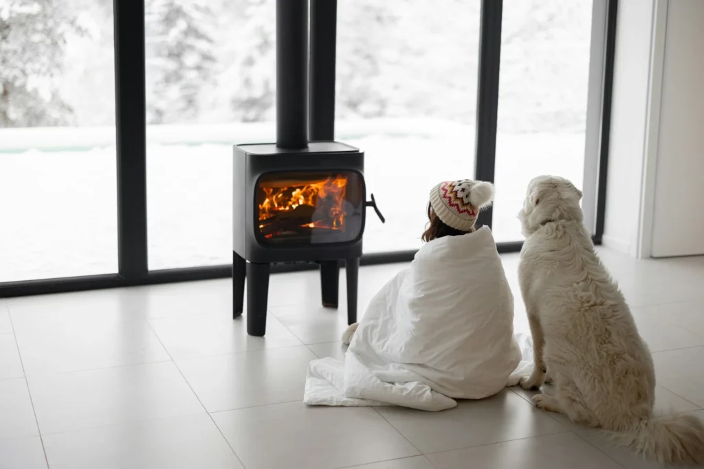 Woman and dog sitting in front of wood burning furnace