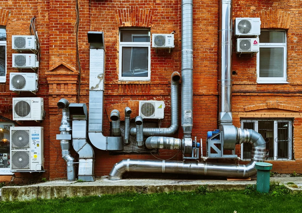 Grey furnace pipes against red brick wall